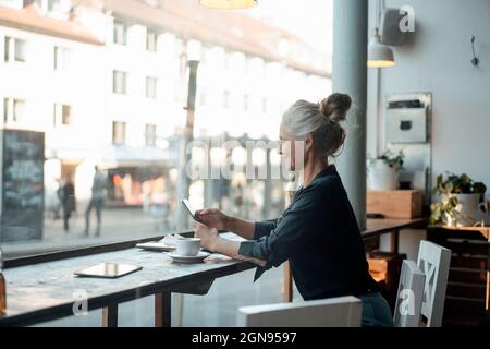 Femme d'âge mûr tenant une tasse dans un café Banque D'Images
