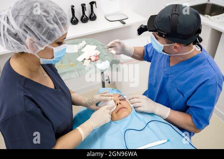 Le chirurgien suture la paupière après une opération de chirurgie plastique Banque D'Images
