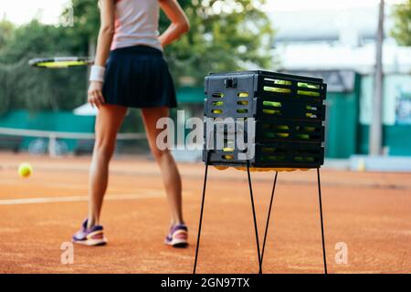 Balles de tennis dans une boîte avec sportswoman pratiquant en arrière-plan Banque D'Images