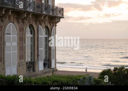 Luxueux balcon donnant sur la Manche au coucher du soleil, un homme court sur la plage Banque D'Images