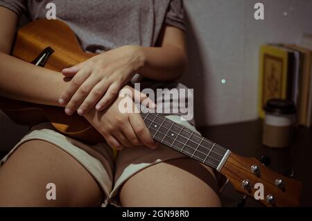 Les mains de la fille se replient sur un ukulele en bois, gros plan Banque D'Images