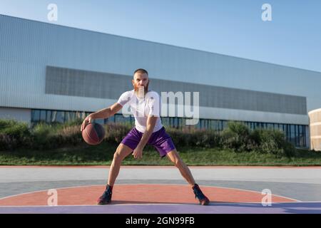 Ballon de sport concentré tout en jouant au basket-ball sur le terrain de rue Banque D'Images