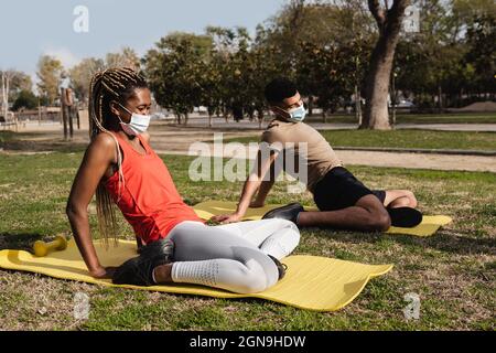 Les Noirs font le yoga routine en plein air tout en portant des masques de sécurité en plein air au parc de la ville - Focus sur le visage de fille africaine Banque D'Images