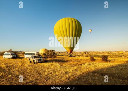 Deux ballons à air chaud se déloquant ou atterrissent dans un champ. L'un est sur le sol. L'autre est en vol avec un membre de l'équipage dans le véhicule prêt à supporter dans Cap Banque D'Images
