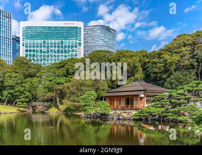 tokyo, japon - octobre 28 2020 : bassin Shiori-no-ike des jardins de Hama-rikyū reflétant dans l'eau les bâtiments et un chashitsu traditionnel japonais te Banque D'Images