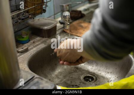 Lavage des mains dans l'évier. Le Bachelor lave ses doigts avec du savon. Lavabo sale dans la maison. De l'eau coule du robinet. Banque D'Images