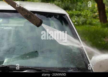 Nettoyer le pare-brise de la saleté. La voiture est lavée par la pression des murs. Entretien des véhicules après une route boueuse. Banque D'Images