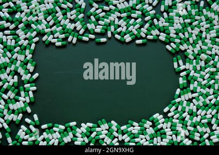 Pilules cadre.Homéopathic herbes vertes capsules sur fond vert. Médecine et homéopathie . Médecine alternative. Pilules vertes fond avec place Banque D'Images