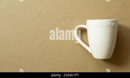 Tasse blanche isolée sur fond marron. Vue du dessus, espace de copie Banque D'Images