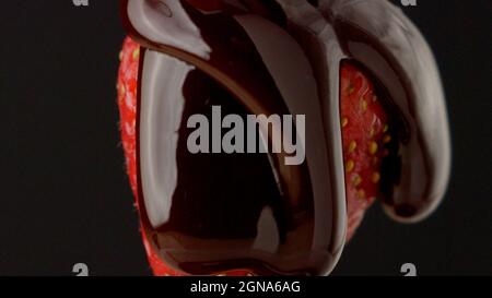 Le chocolat coule sur la fraise gros plan macro liquide goutte chocolat doux Banque D'Images