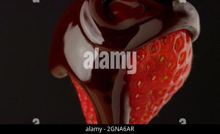 Le chocolat coule sur la fraise gros plan macro liquide goutte chocolat doux Banque D'Images