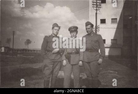 Un père fier (qui est policier / officier de police) se tient avec ses deux fils cadets qui les passaient du temps obligatoire à l'armée hongroise dans les années 1950 La période de service militaire était de 3 ans à cette époque. / homme vintage fumant une cigarette Banque D'Images