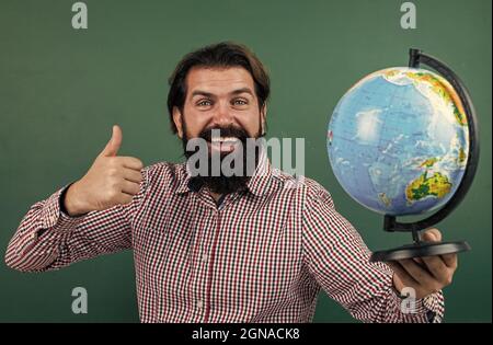 concept de voyage. réussir l'examen. apprendre le sujet. retour à l'école. joyeux jour des enseignants. homme brutal avec barbe tenir la carte du globe géographique. informel Banque D'Images