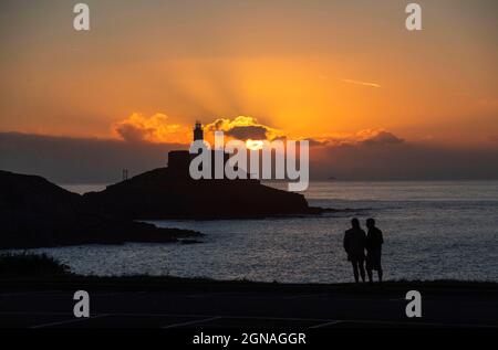 Swansea, Royaume-Uni. 24 septembre 2021. Ce matin, les gens marchent à Bracelet Bay tandis que le soleil se lève au-dessus du phare de Mumbles sur la péninsule de Gower, près de Swansea. Credit: Phil Rees/Alamy Live News Banque D'Images