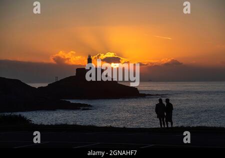 Swansea, Royaume-Uni. 24 septembre 2021. Ce matin, les gens marchent à Bracelet Bay tandis que le soleil se lève au-dessus du phare de Mumbles sur la péninsule de Gower, près de Swansea. Credit: Phil Rees/Alamy Live News Banque D'Images