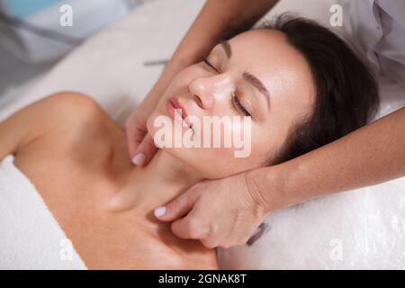 Belle femme mûre se relaxant au spa, se faire masser le cou Banque D'Images