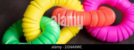 enfants anti stress sensoriel pop tube en plastique jouet pouget sur une table noire ou fond de sol. enfants petits jouets poptube multicolore hue bright col Banque D'Images