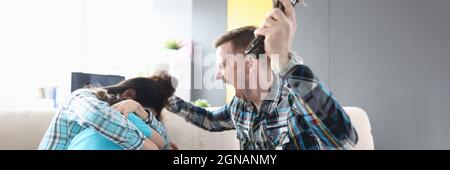 Un homme en colère hurle devant sa femme et son enfant tenant la ceinture dans sa main Banque D'Images