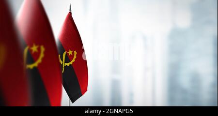 Petits drapeaux de l'Angola sur un fond flou de la ville Banque D'Images