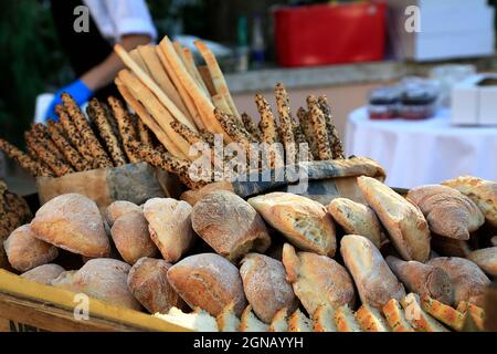 pains de pain de blé frais croquant sur la tablette du marché électronique. Bâtonnets de pain et baguette en arrière-plan. Marché le dimanche matin. Casarecio italien traditionnel Banque D'Images