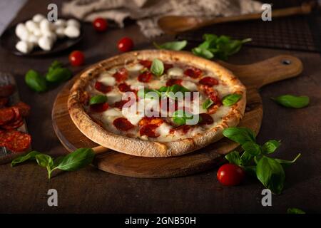 Pizza délice avec salami chaud, parmesan et basilic frais Banque D'Images