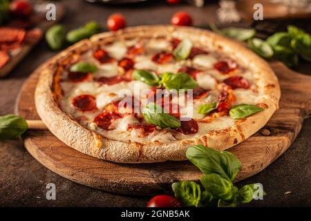 Pizza délice avec salami chaud, parmesan et basilic frais Banque D'Images