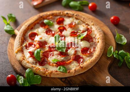 Pizza délice avec salami chaud, parmesan et basilic frais Banque D'Images