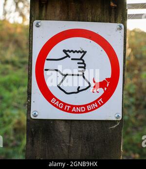 Un panneau sur un poteau en bois indiquant « sac et poubelle » concernant les déchets de chien, Angleterre, Royaume-Uni Banque D'Images