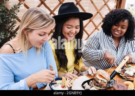 Jeunes amis multiraciaux ayant le petit déjeuner à l'extérieur dans le restaurant - Focus dans le visage asiatique de fille Banque D'Images