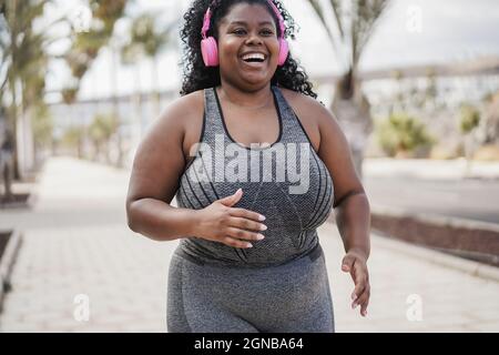 Femme africaine curvy jogging en plein air au parc de la ville - Focus sur la face Banque D'Images