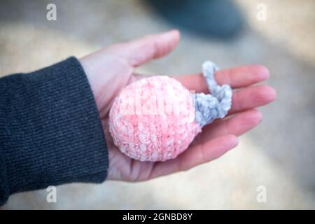 Rose nouvel an boule amigurumi dans la main de la femme dehors. Tricoté en fil de peluche doux pour la décoration de Noël. Cadeaux de Noël faits main. Création Banque D'Images