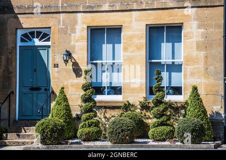 Une maison Cotswold avec différentes formes topiaires dans le jardin avant. Banque D'Images