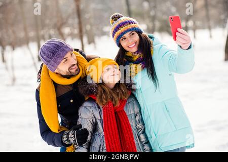 Photo de famille belle maman papa fille heureux sourire positif faire selfie téléphone portable vacances hiver voyage à l'extérieur Banque D'Images