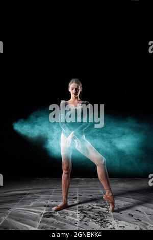 Magnifique danseur de ballet posé sur des Pointes. Ballerine portant un body noir isolé sur fond de studio noir, dansant avec de la farine. Por. Pleine longueur Banque D'Images