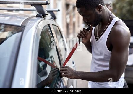 Voleur vol de voiture casser la porte criminel travail cambriolage randonneurs Auto voleur en port noir, essayant de casser dans l'automobile à l'aide d'outils. Violence de la criminalité de rue g Banque D'Images