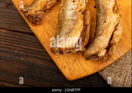 Petit poisson frit sur un panneau en bois, gros plan, sélectif Banque D'Images