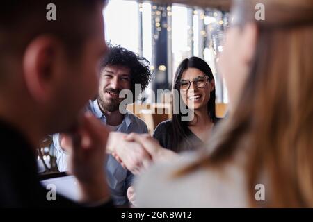 Jeunes gens d'affaires ayant une réunion créative dans un café. Des expressions souriantes et souriantes. Banque D'Images