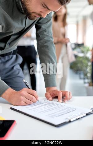 Homme d'affaires à la réunion d'affaires après des négociations réussies prêt à signer l'accord papier officiel gros plan sur les mains de femme d'affaires tenant pe Banque D'Images