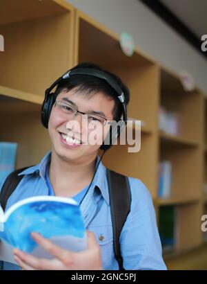 un étudiant de l'université lit un livre et écoute de la musique à la bibliothèque Banque D'Images