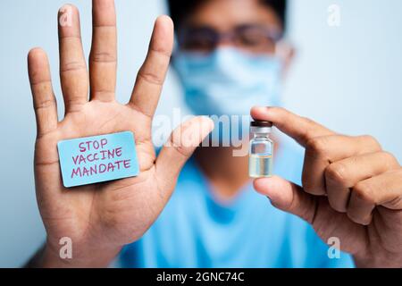 Concentrez-vous sur les mains, jeune homme avec masque médical montrant le mandat d'arrêt de vaccin - concept d'hésitation de vaccin. Banque D'Images