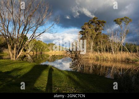 Des nuages s'amassent au-dessus de la rivière Klein, de la chaîne de montagnes et d'une eau calme et plate. Banque D'Images