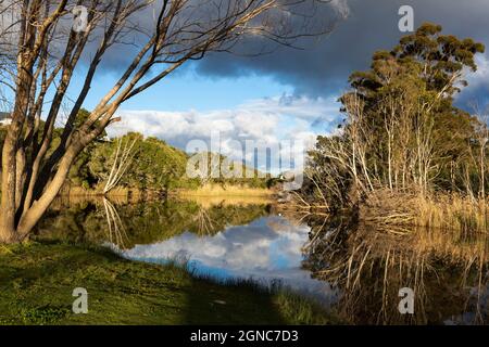 Des nuages s'amassent au-dessus de la rivière Klein, de la chaîne de montagnes et d'une eau calme et plate. Banque D'Images