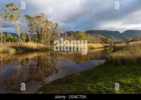 Des nuages s'amassent au-dessus de la rivière Klein, de la chaîne de montagnes et d'une eau calme et plate. Banque D'Images