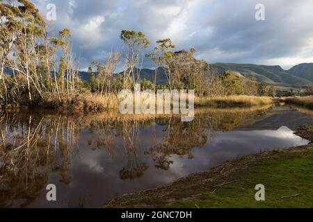 Des nuages s'amassent au-dessus de la rivière Klein, de la chaîne de montagnes et d'une eau calme et plate. Banque D'Images