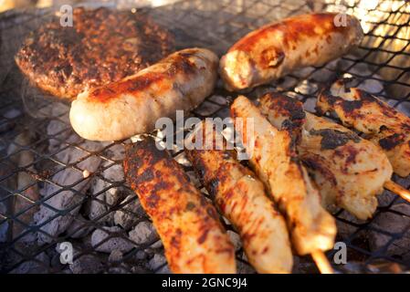 La viande étant cuite sur un barbecue disposible, sur la plage. Angleterre, Royaume-Uni. Hamburger, saucisses, kebabs. Banque D'Images
