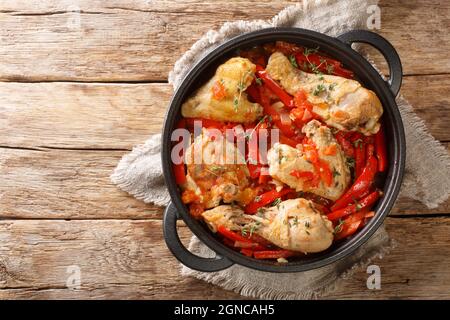 Poulet braisé basque au poulet aux poivrons poulet basquaise gros plan dans la casserole sur la table. Vue horizontale du dessus Banque D'Images