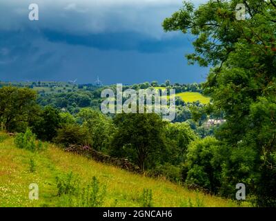 Vue sur les champs en direction de Starkholmes et Matlock Bath dans le Derbyshire Dales Peak District Angleterre Royaume-Uni avec des arbres et le ciel orageux avant la pluie. Banque D'Images