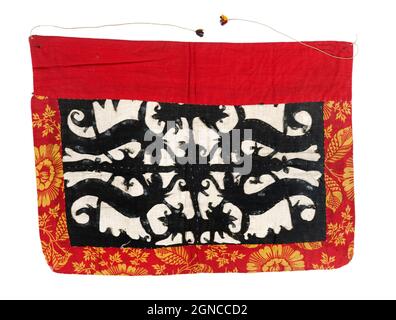 Une jupe en coton tissé. Le bord supérieur est rouge, le bord inférieur et les bords latéraux sont rouges avec des fleurs jaunes. Le centre est blanc, avec quatre figurines stylisées en surpiqûre noire. Les cordes sont faites de fil jaune et se terminent en touffes multicolores. La jupe est utilisée pour habiller le défunt. Banque D'Images