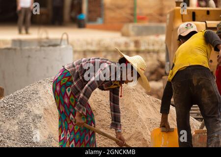 Indein Village, Myanmar - 05 janvier 2020 : portrait d'une jeune femme travaillant sur un chantier de construction, en ramasse du sable dans un seau, État Shan Banque D'Images