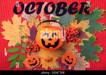 Le 31 octobre est la date d'Halloween. Lanterne Jack o Halloween avec bonbons sur un fond d'automne coloré de feuilles séchées, baies rowan orange Banque D'Images